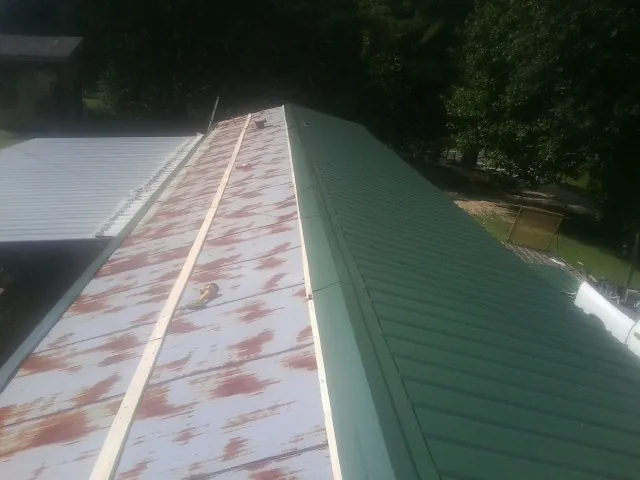 Old rusted panels beside newly installed green metal roofing — Wind Damage Roof Repair by Roofing Brothers in Harrisville