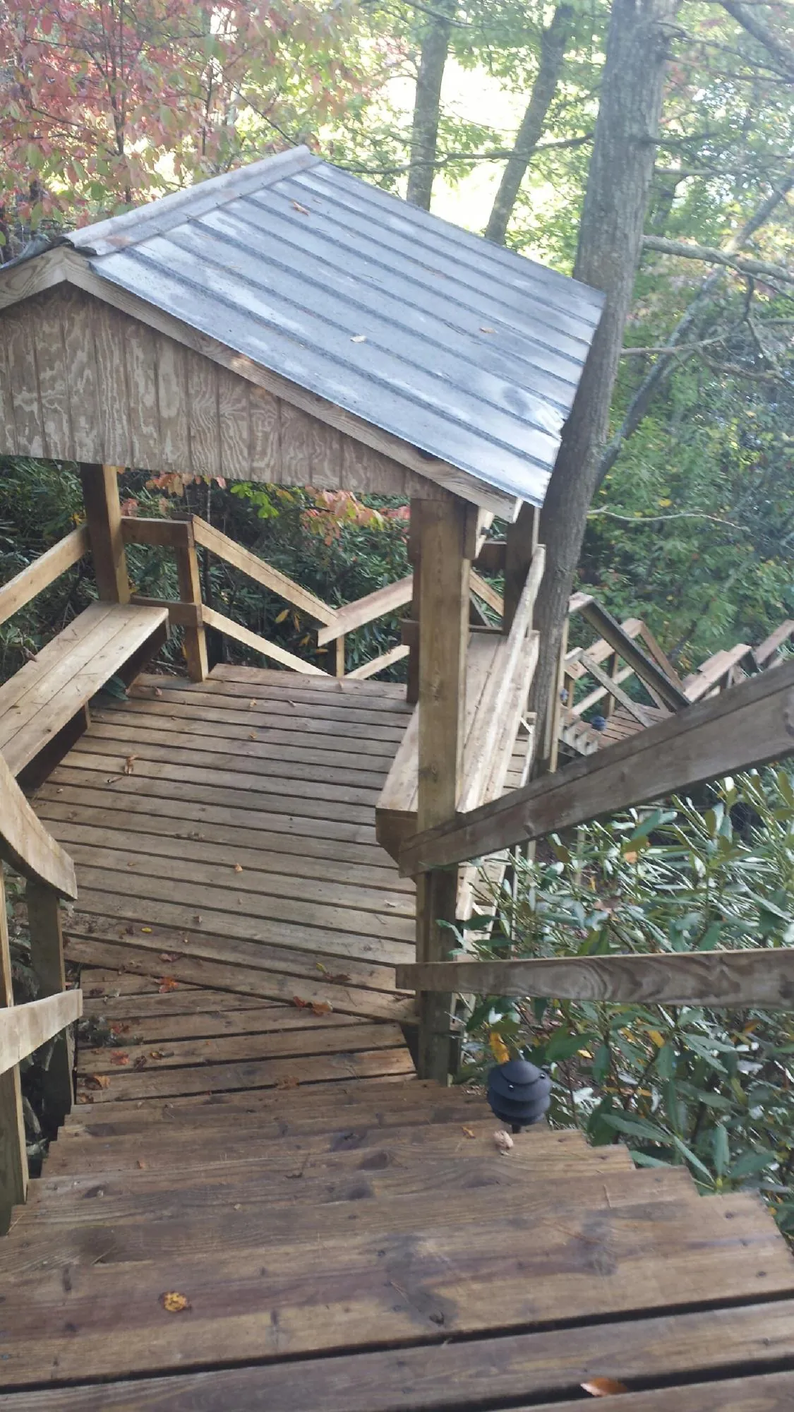 Metal roofed shelter over wooden steps on a wooded walkway — Skylight Repair & Installation work by our crew in Harrisville